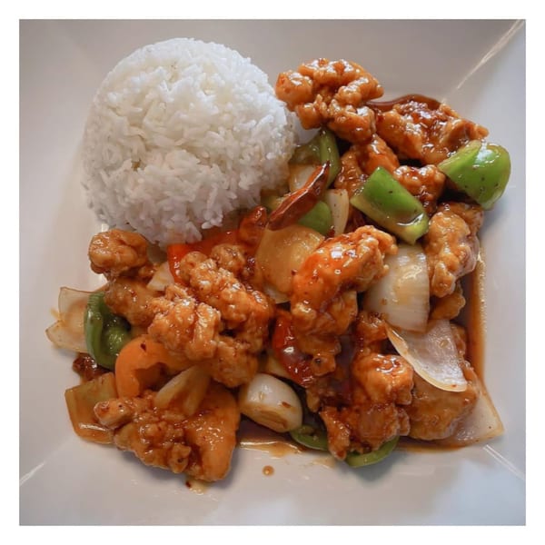 Sweet and sour chicken with bell peppers, onions, and a side of white rice.