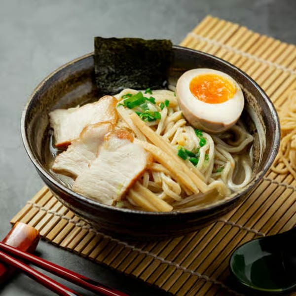 A bowl of Wabi Sabi ramen with pork, bamboo shoots, nori, and a soft-boiled egg.