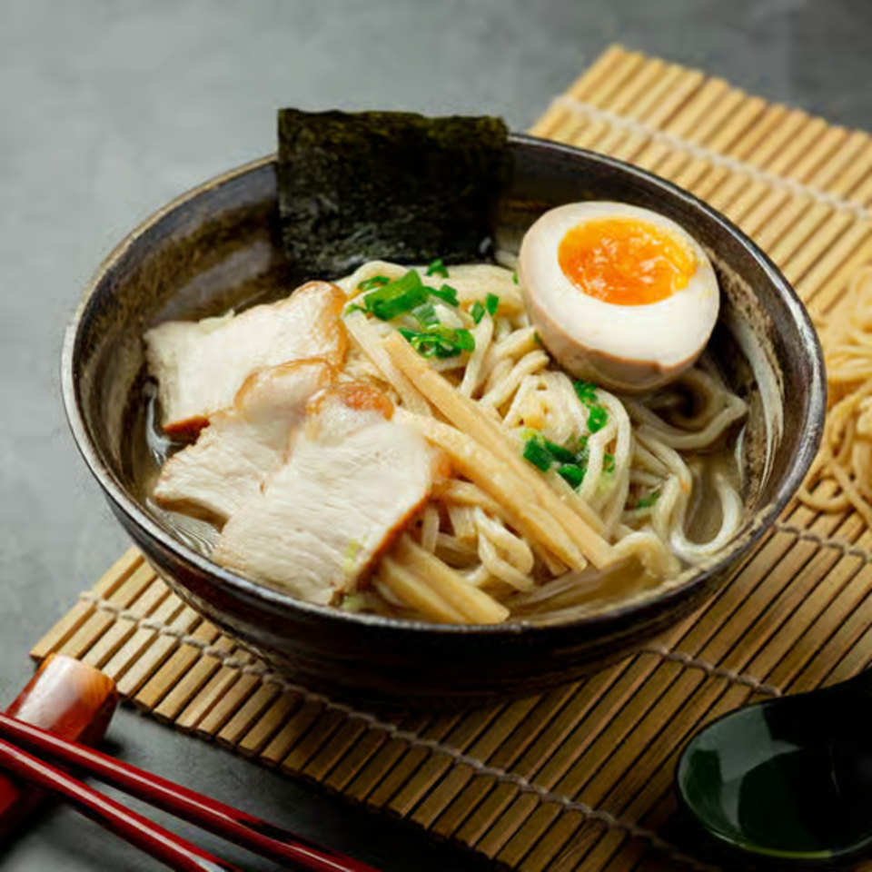 A bowl of Wabi Sabi ramen with pork, bamboo shoots, nori, and a soft-boiled egg.