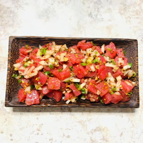 Wabi Sabi's tuna poke with diced onions and green onions in a dark wooden dish.